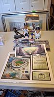 Photo of baseball figurines, bobbleheads, coins, and framed Yankee Stadium prints arranged on a table.
