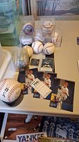 Multiple baseballs in display cubes and loose on table with autographed photos