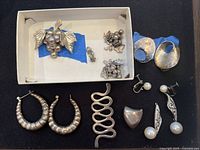 All items arranged on black surface and boxed, showing damaged and tarnished sterling silver jewelry.