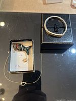 Full display of gold jewelry set including the fish pendant on a chain, the stretch ankle bracelet, and the small piles of pendants.