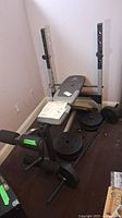 Full view of the Gold's Gym XR7.9C weight bench with barbell, weights stacked beside bench, and instruction manual on seat.