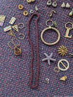 Overview of costume jewelry items including necklace, bracelets, earrings, and pins on patterned carpet