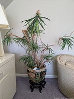 Full view of the faux plant in the Asian style planter on wooden base.