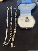 Overview of three bracelets and a heart pendant necklace inside a jewelry box, showing overall lot contents.