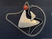 Front view of abstract triangular silver pendant with carnelian stone on curb chain