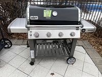 Front view of grill showing hood, control panel, side shelves and wheels