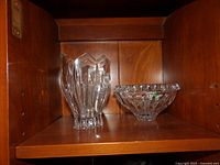 Clear crystal vase and bowl on a wooden shelf showing geometric and cut designs.