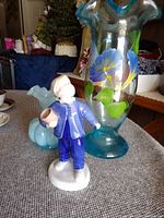 Porcelain figurine, small blue flared vase, and tall hand-painted blue fluted vase shown together on a table.