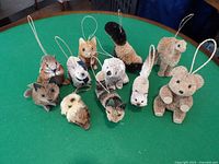 Photo showing 11 bottle brush animal ornaments including a bear, rabbit, owl, skunk, and others arranged on a green table.