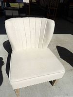 Front view of cream upholstered occasional chair showing vertical channel tufting on backrest and wooden legs.