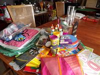 Craft supplies and activity materials for children arranged on a dining table including Play-Doh tubs, glue bottles, paper plates, coloring books, and a Kids Crafts holder.