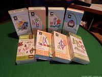 Photo of 8 Cricut cartridge boxes arranged on a table showing front covers with various colorful designs.