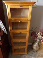 Front view of tall wooden DVD/CD cabinet with five glass doors and metal knobs.