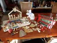 Overall assortment of home décor items arranged on a wooden table including nativity set, angels, and other figurines with assorted ornaments.