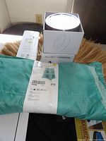 Boxed Ikea Allbey Vimmern mirror and folded turquoise curtain panel on woven mat