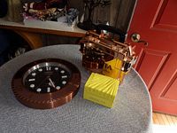 Invicta wall clock with black dial and rose gold case placed on a round table with rose gold watch holders.