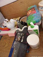 Photo showing white bird ceramic container, perfumes, lotion, bath sponges, earrings and jar of bath salts/body cream.