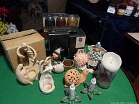 Wide view of the assortment showing multiple figurines, candle holders, a Game of Thrones candle set, and a large pillar candle.