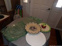 Photo of all serving platters including two clear glass platters, white ceramic platter, floral ceramic bowl, and apple-themed ceramic plate