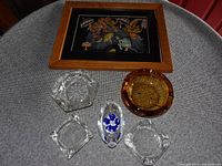 Full view of framed vintage Asian print and five ashtrays arranged on a gray surface
