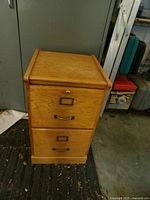 Full view of the wooden 2-drawer file cabinet showing lock, handles, and label holders