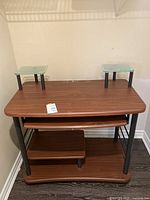 Front view of the computer desk with wood veneer surface, two raised glass platforms, pullout tray, and lower shelf.