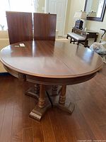 Full view of round table assembled with two leaves resting behind.