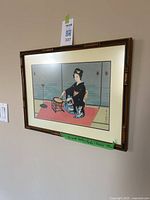 Framed art print featuring a Japanese Geisha playing drums, displayed on a wall. Frame is faux bamboo style.