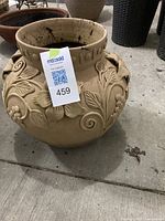 Full view of a tall clay garden pot with label showing lot number 459, decorated with raised floral designs and natural beige clay color.