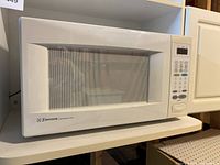 Front and side view of the white Emerson microwave showing the model and control panel.
