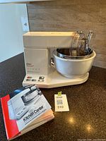 Side view of Oster Kitchen Center kitchen appliance with bowl and instructions on counter