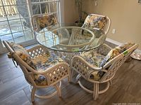 Overall view of round glass table and four floral bamboo chairs
