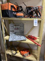 Full view of the Ridgid 18V cordless tools, battery charger, batteries, tool bag, drill bit sets, and some additional hand tools on shelving.