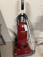 Full view of the Kenmore Intuition upright vacuum cleaner showing its red color, handle, hose, and overall condition.