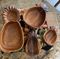 Overview of five wooden pineapple-shaped serving dishes varying in size.