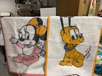 Photo showing two vintage Disney baby blankets side by side, featuring Minnie Mouse and Pluto with distinctive colored borders.