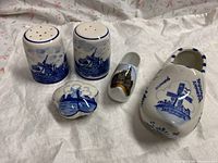 Photo showing all four blue Delft ceramic items: salt and pepper shakers, lidded trunk dish, large and small decorative shoes