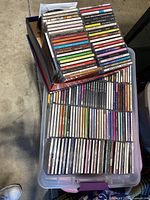 Two containers filled with stacked CD jewel cases arranged spine-up revealing artist and album titles.