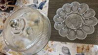 Photo of clear glass footed cake plate with dome cover and vintage deviled egg dish showing overall shapes and patterns.