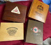 Top view of 4 vintage wooden cigar boxes showing logos of Montecristo Serie V, Casa H. Upmann, Joya de Nicaragua imported, and Joya de Nicaragua 1976.