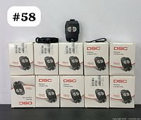 10 boxed DSC PG8949 wireless panic buttons arranged 5 above 5 with one unit outside the boxes showing front face with two buttons labeled lock/unlock.