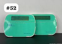 Two Tyco integrated security alarm keypads with LCD displays shown closed side-by-side on black surface.