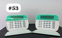 Front view of the two Tyco security alarm keypads side by side, showing the green-tinted LCD display covers and numeric keypads.