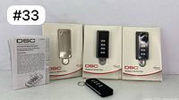 Three DSC 4-button wireless remote controls, two in original boxes, one with keychain, plus instruction manual.