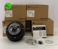 Photo showing one black dome camera with clear bubble, original boxes stacked behind, and accessories laid out