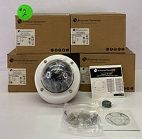 Four boxed American Dynamics Discover 300 Series outdoor dome cameras with one removed from box showing white dome casing and smoked lens cover, with accompanying accessories including installation guides and mounting hardware.