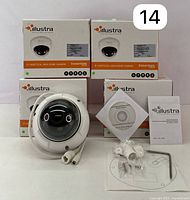Set of four Illustra Essentials IP varifocal mini-dome cameras in their original packaging, one camera and installation accessories displayed in front.