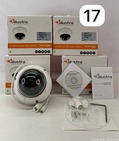 Set of 4 Illustra Essentials IP Varifocal Mini-Dome Camera boxes stacked behind one visible camera with cables and mounting accessories in front