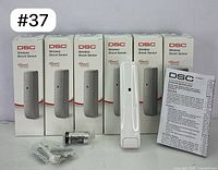 Six boxed DSC Wireless Shock Sensors with one sensor, battery, mounting screws, and user manual displayed in front.
