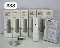 All six DSC Wireless Shock Sensors in their boxes, displayed alongside one sensor, battery, screws, and instruction manual.